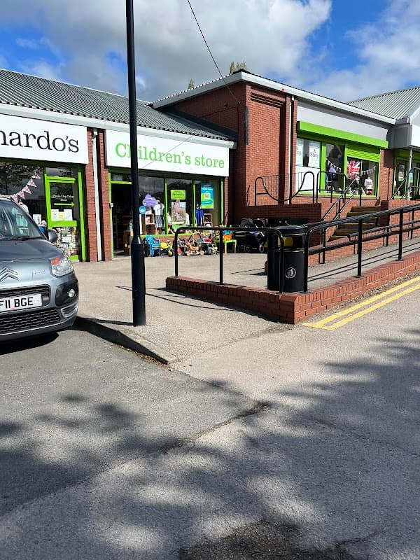 Barnardo's Children's Store with green signage, toys outside, and a ramp, set in a sunny Yorkshire street.