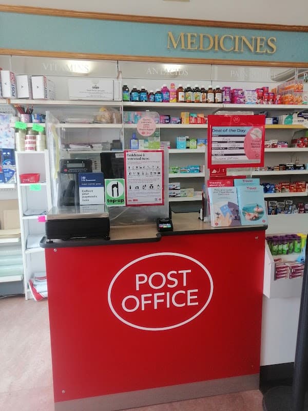 Post office counter with red signage, medicine shelves, and promotional displays in a bright, organized space.