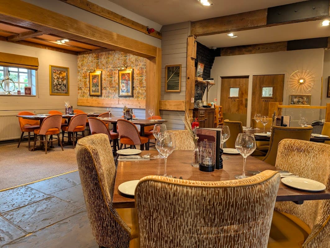 Cozy restaurant interior with wooden beams, elegant tables set with glassware, and warm lighting in Mosborough, Yorkshire.