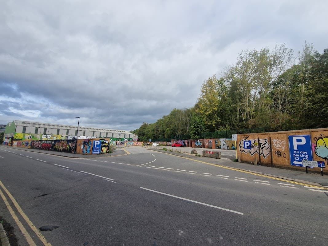Pay & Display car park on Boyland Street, surrounded by colorful graffiti and trees under a cloudy sky.