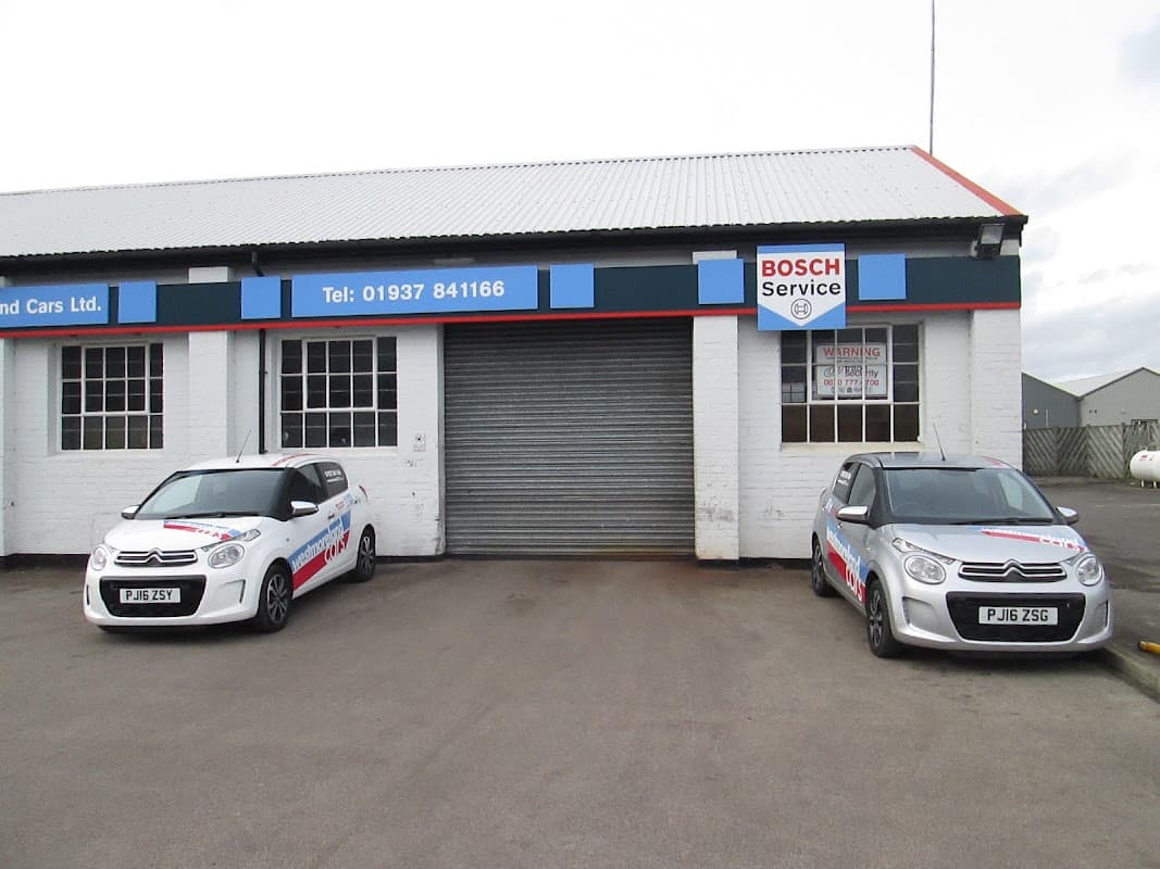Westmoreland Cars Ltd shopfront with two cars parked outside, featuring Bosch Service signage and a shuttered entrance.