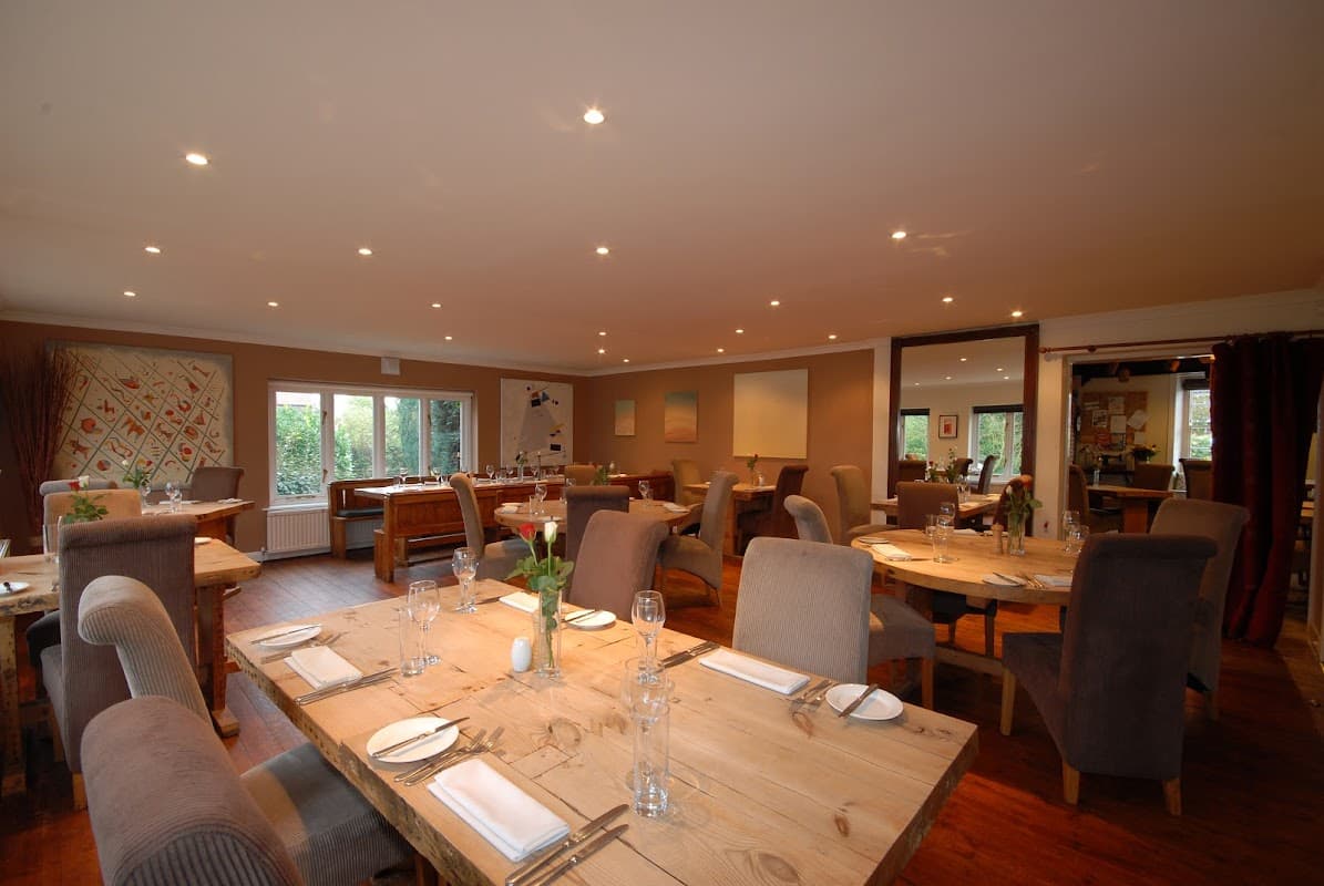 Cozy restaurant interior with wooden tables, upholstered chairs, and soft lighting, featuring a welcoming atmosphere.