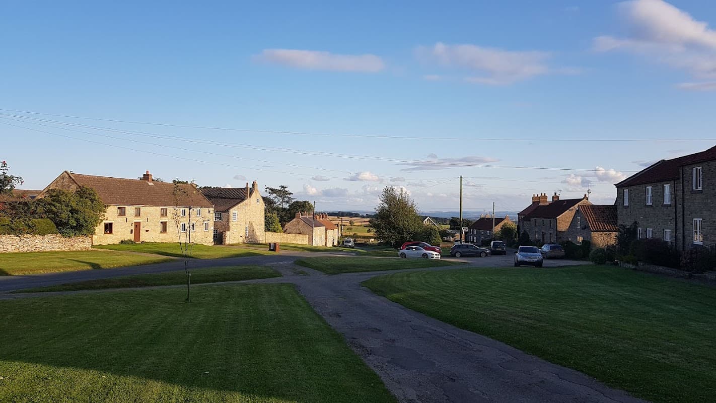 Granary Manor Farm in Newton-upon-Rawcliffe, featuring stone buildings, grassy areas, and a clear blue sky.