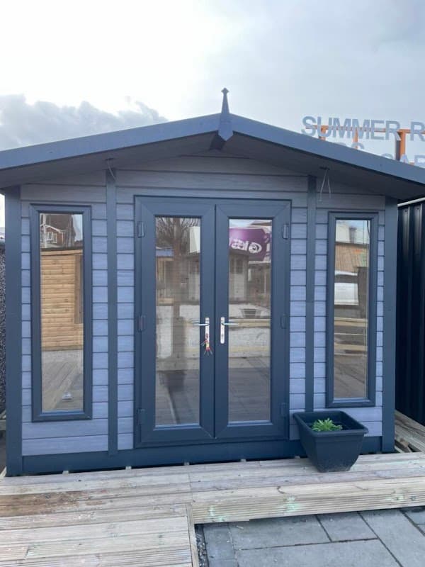 A modern wooden garden building with large windows and a double door, set on a wooden deck.