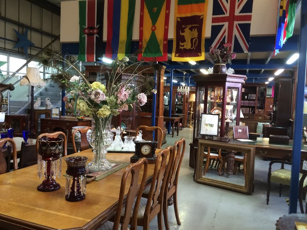 Antique shop interior with wooden furniture, decorative vases, and various flags hanging from the ceiling.