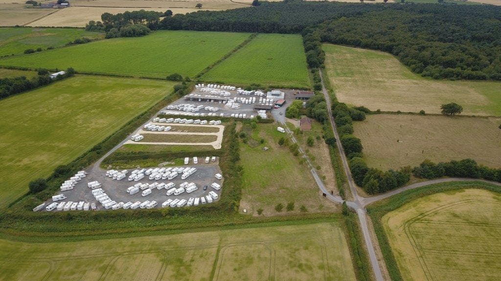 Aerial view of Moorlands Secure Storage, featuring numerous parked vehicles and green fields in North Newbald, Yorkshire.