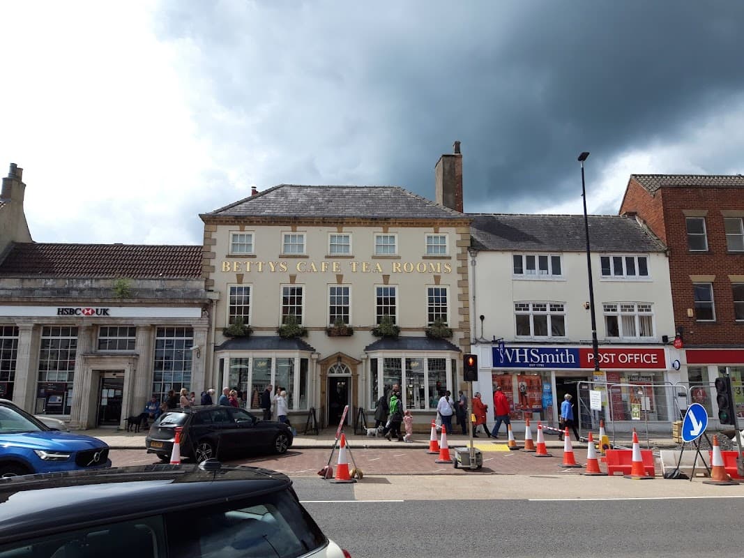 Betty's Café Tea Rooms with pedestrians, cars, and construction cones outside in Northallerton, Yorkshire.