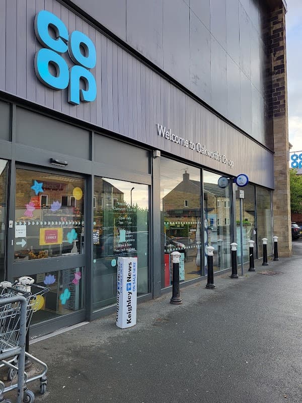 Co-op Food store entrance with signage, shopping carts, and decorative window displays in Oakworth, Yorkshire.