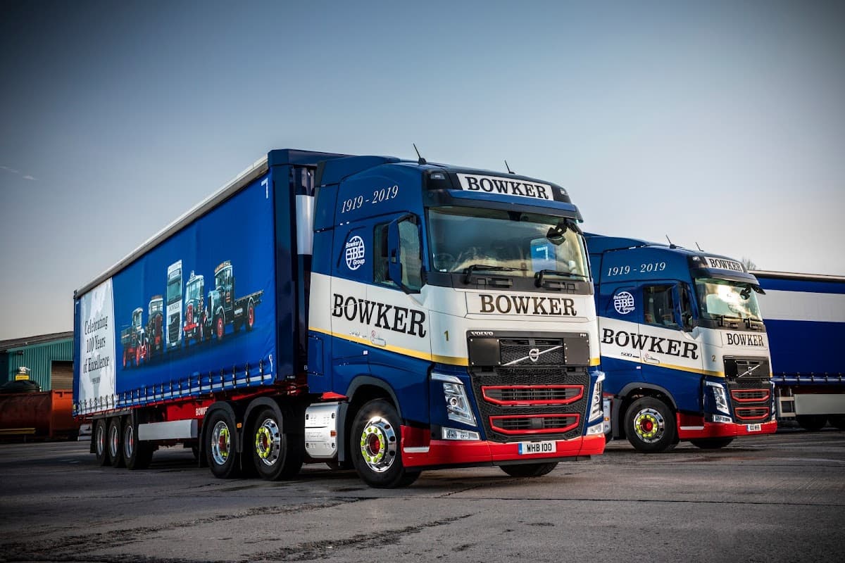 Two blue and white Bowker Group trucks parked, showcasing the company logo and a commemorative design for 1919-2019.