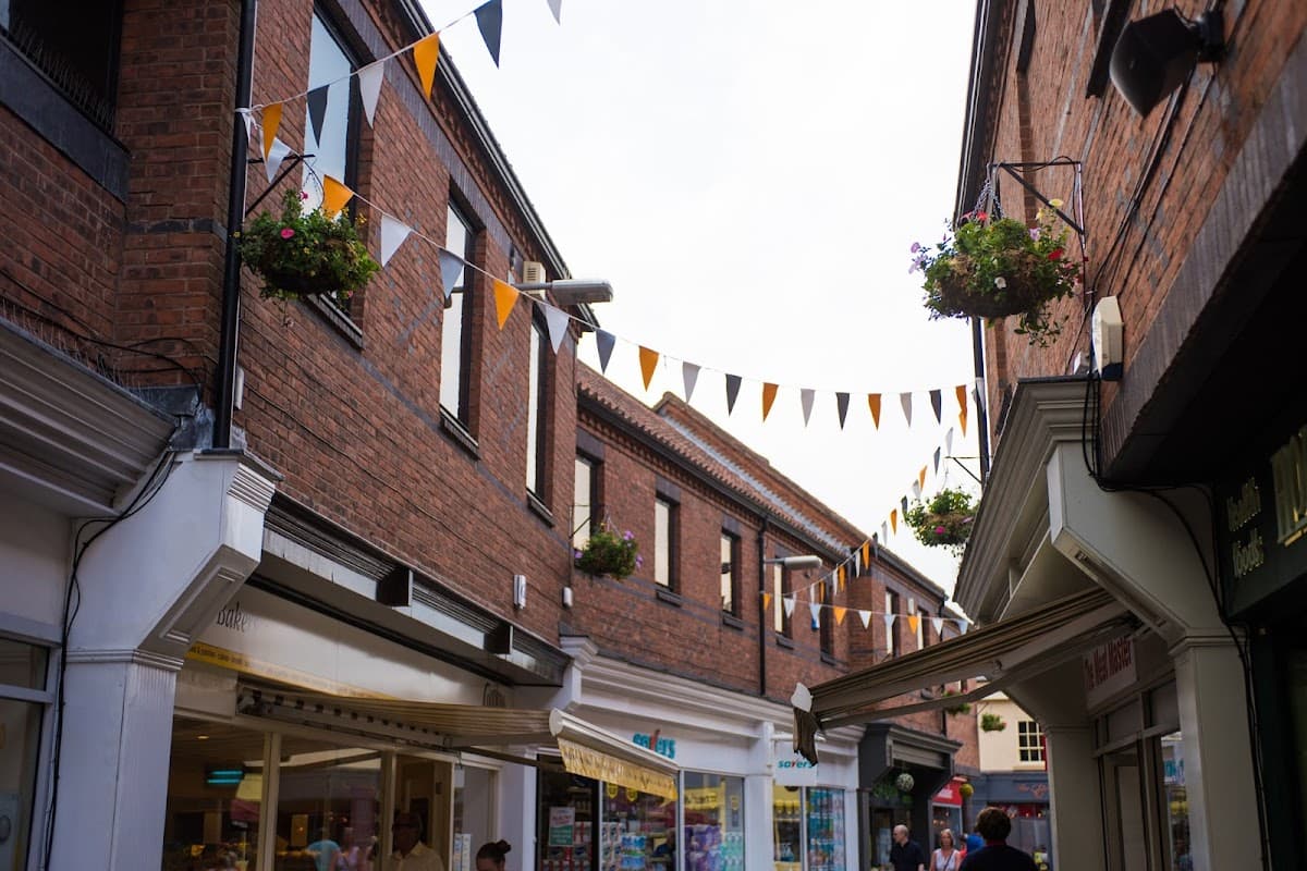 Brick buildings with hanging flower baskets and bunting flags, creating a vibrant shopping atmosphere in Osgodby.