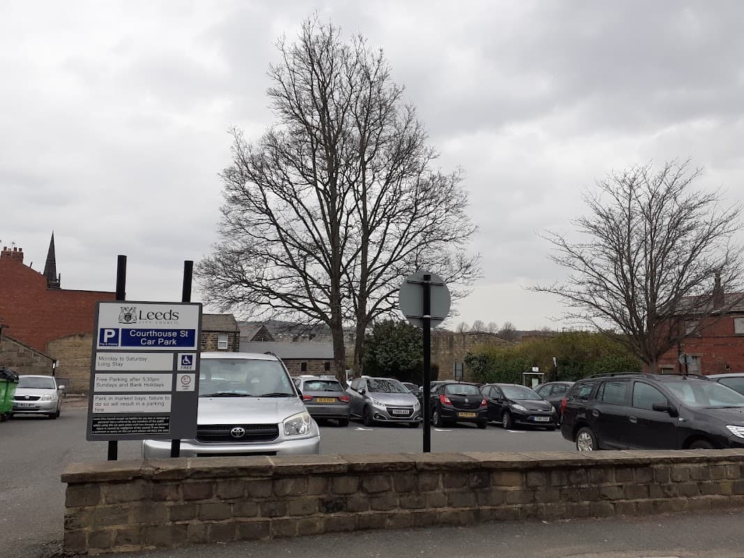 Courthouse Street Car Park with parked cars, a large tree, and a sign indicating parking rules under a cloudy sky.
