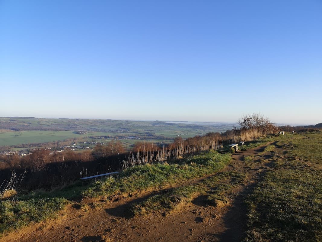 Scenic view from East Chevin Quarry Car Park, overlooking green hills and valleys under a clear blue sky.
