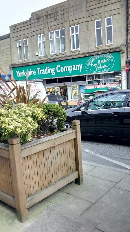 Yorkshire Trading Company storefront with green signage, potted plants, and parked cars in front.
