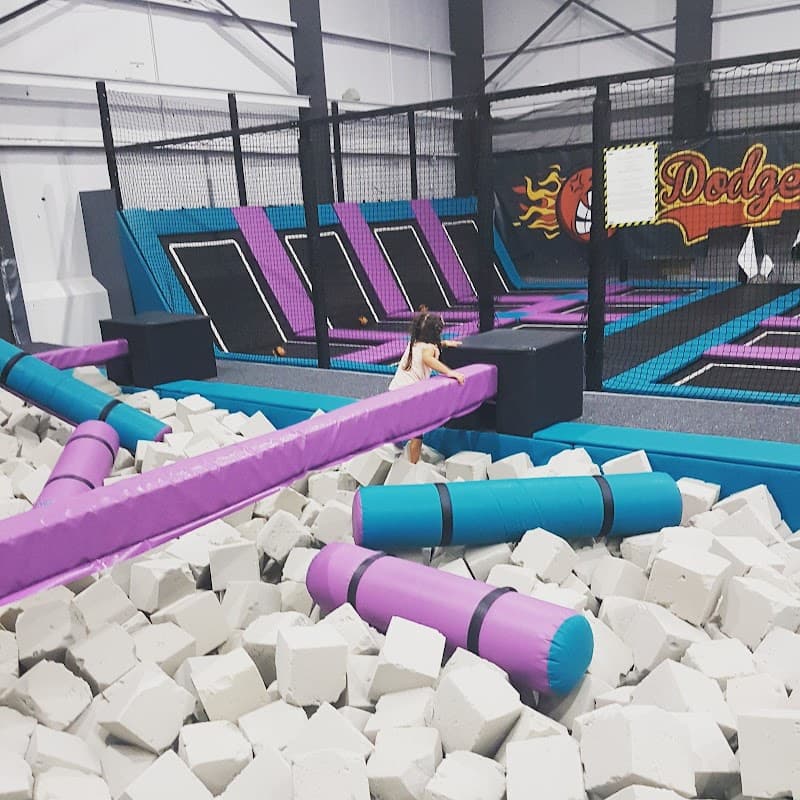Trampoline park featuring colorful trampolines, foam blocks, and a child navigating a play area.
