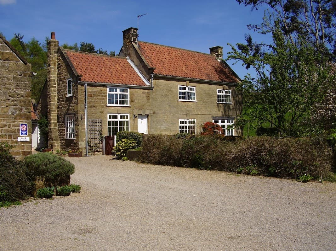 Charming stone farmhouse with a red-tiled roof, surrounded by greenery and a gravel driveway in Over Silton, Yorkshire.