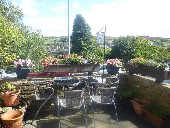 Outdoor seating area with a table and chairs surrounded by flower pots and scenic views of the Yorkshire countryside.