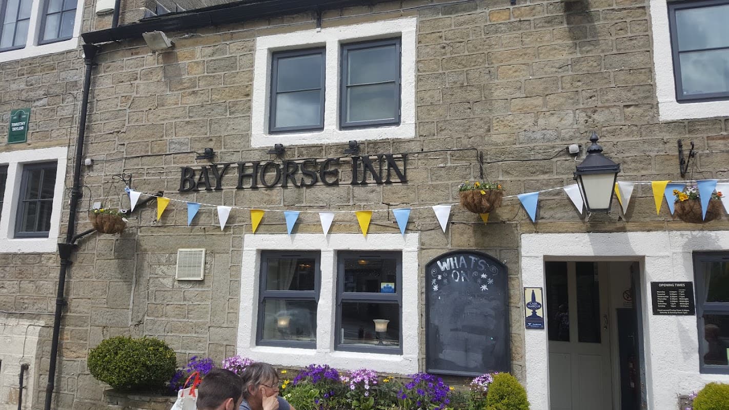 The Bay Horse Inn, a stone building with blue and yellow bunting, flower pots, and a chalkboard menu.