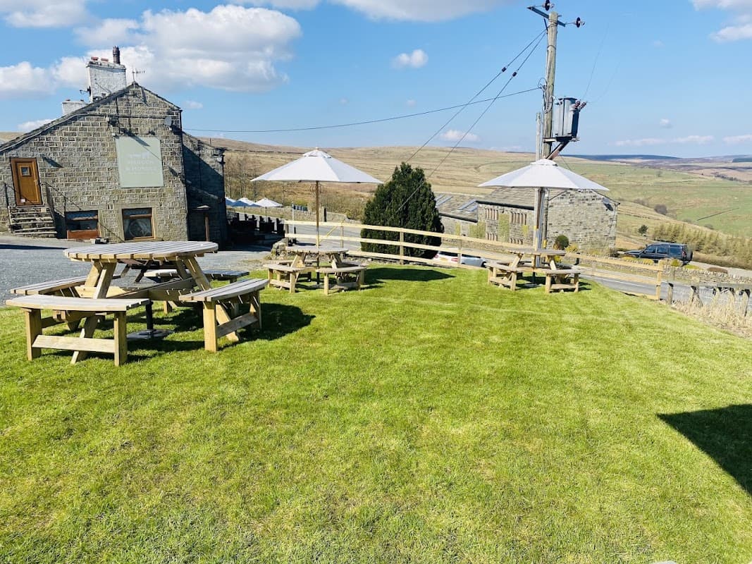 The Waggon & Horses Inn features outdoor seating on a grassy area with umbrellas and scenic Yorkshire hills in the background.