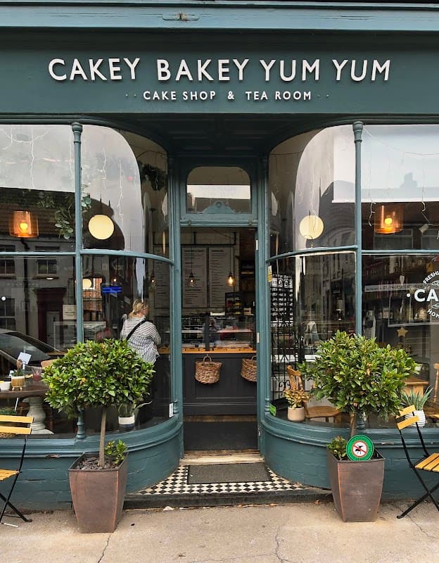 Charming cake shop entrance with large windows, potted plants, and a welcoming sign in Patrington, Yorkshire.