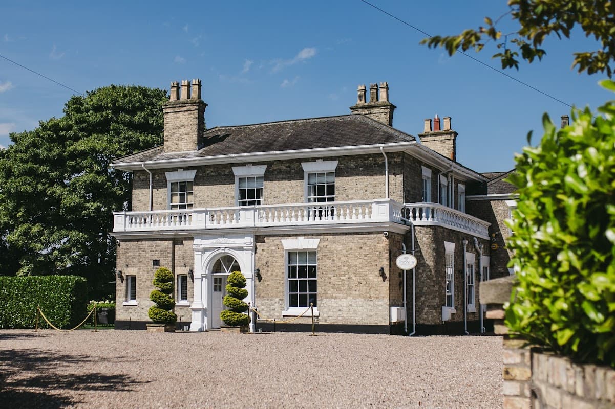 Elegant brick hotel with white trim, manicured hedges, and a sunny blue sky in Patrington, Yorkshire.