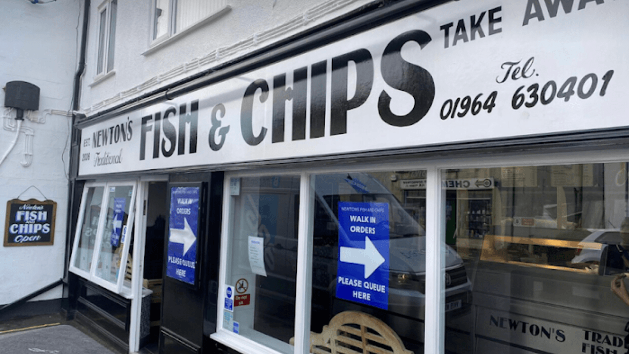Signage for Newton’s Traditional Fish & Chips, featuring large text, takeaway options, and a queueing instruction.
