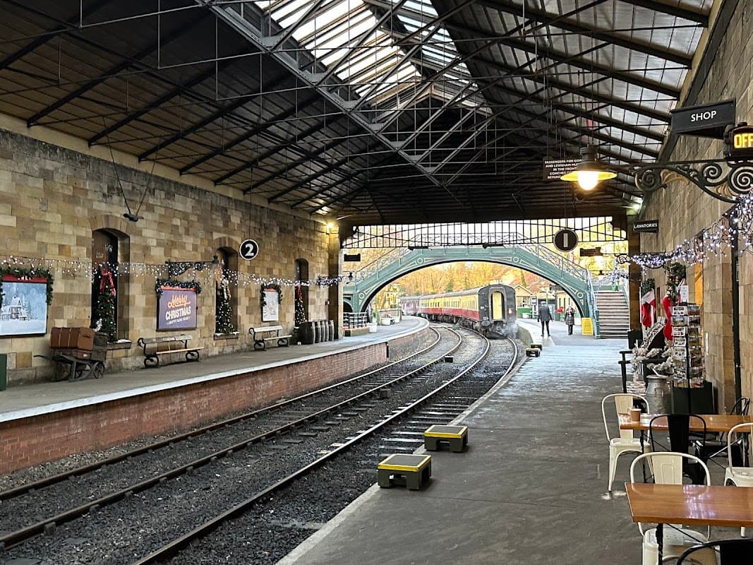 Historic railway station in Pickering, Yorkshire, featuring decorated platforms, tracks, and vintage train carriages.