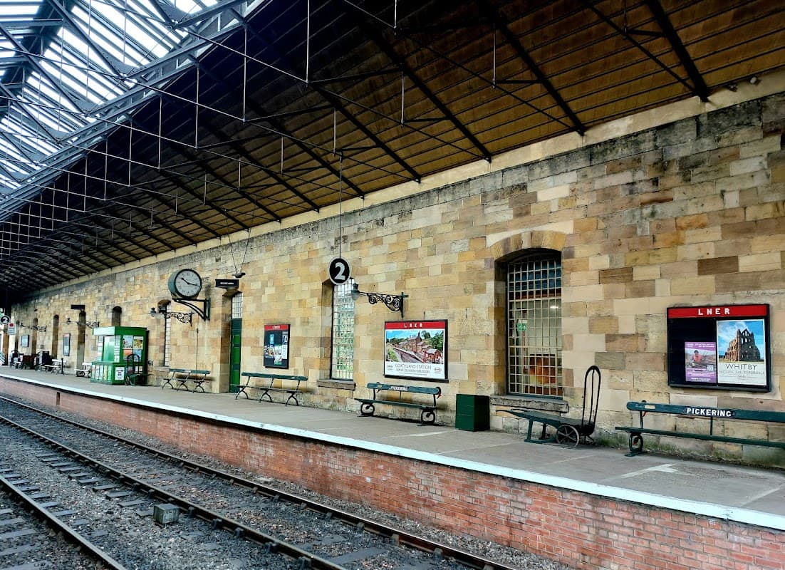 Historic stone platform with benches, vintage posters, and a clock at Pickering Station Tea Room in Yorkshire.