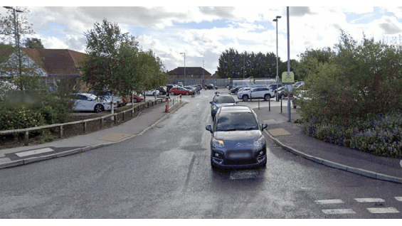 Pay & Display parking area in Pocklington, Yorkshire, with cars parked and greenery along the roadside.