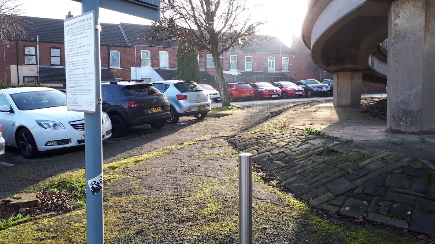 Newgate North Car Park with several parked cars, a sign, and a view of nearby buildings and trees.