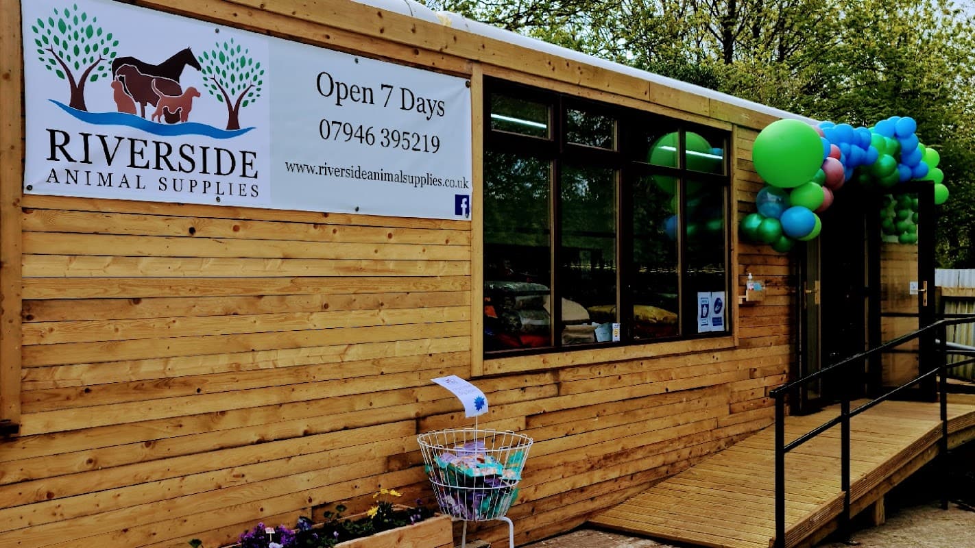 Wooden exterior of Riverside Animal Supplies with colorful balloons, a sign, and a shopping cart outside.