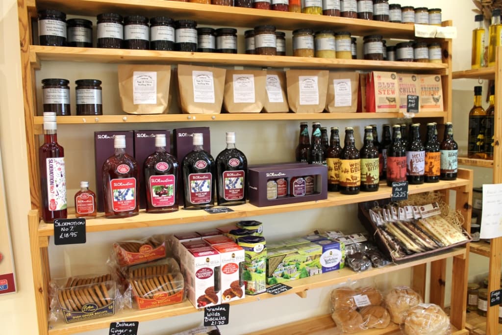 Shelves stocked with jars, bottles, and packaged goods, including jams, biscuits, and drinks at Trotters Farm Shop.