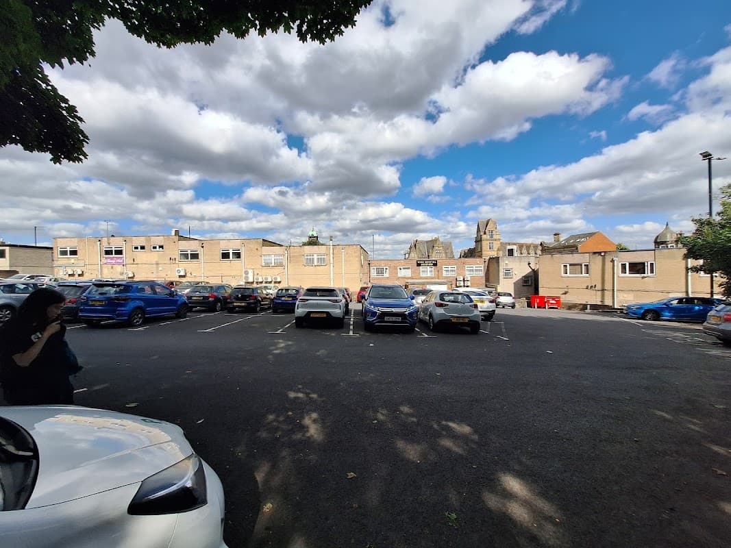 Free parking lot at Lidget Hill, surrounded by buildings and a partly cloudy sky in Pudsey, Yorkshire.
