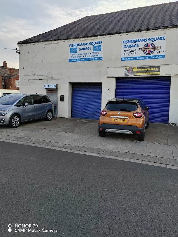 Fishermans Square Garage with blue doors, signage, and parked cars in front on a street in Redcar, Yorkshire.