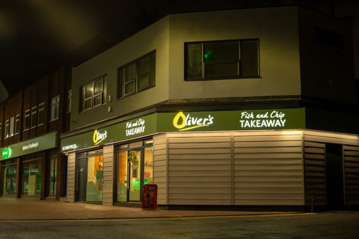 "Oliver's Fish & Chip Takeaway with bright signage, located on a quiet street in Redcar, Yorkshire at night."