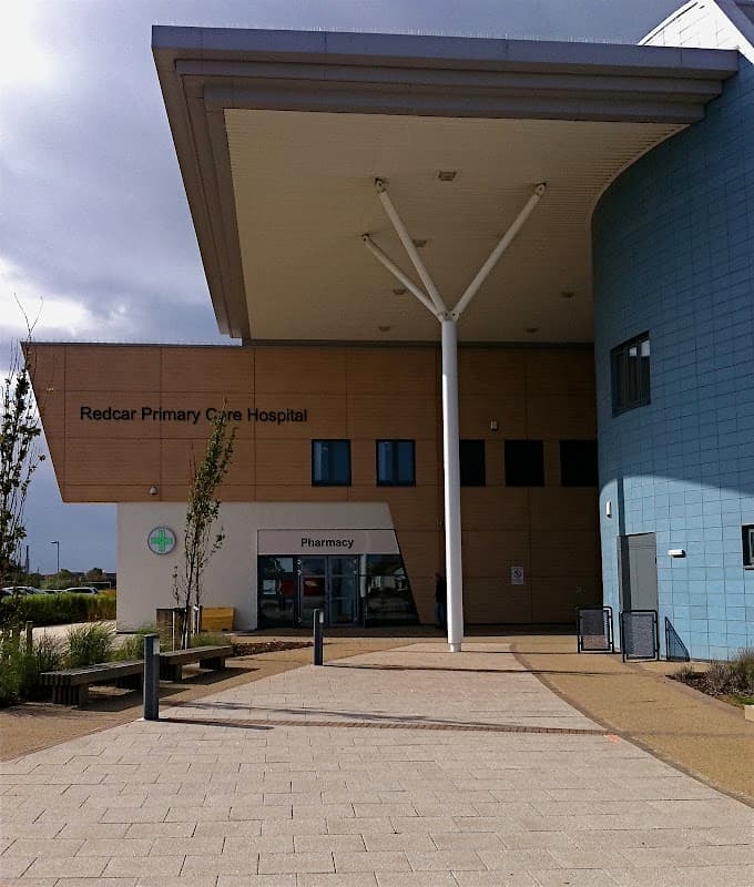 Redcar Primary Care Hospital entrance with modern architecture, large overhang, and pharmacy sign.