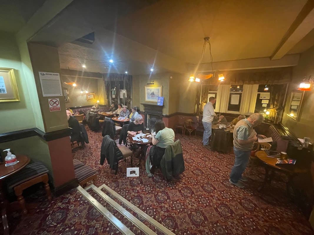 Cozy bar interior with patrons seated at tables, warm lighting, and patterned carpet in The Lobster Inn, Redcar.