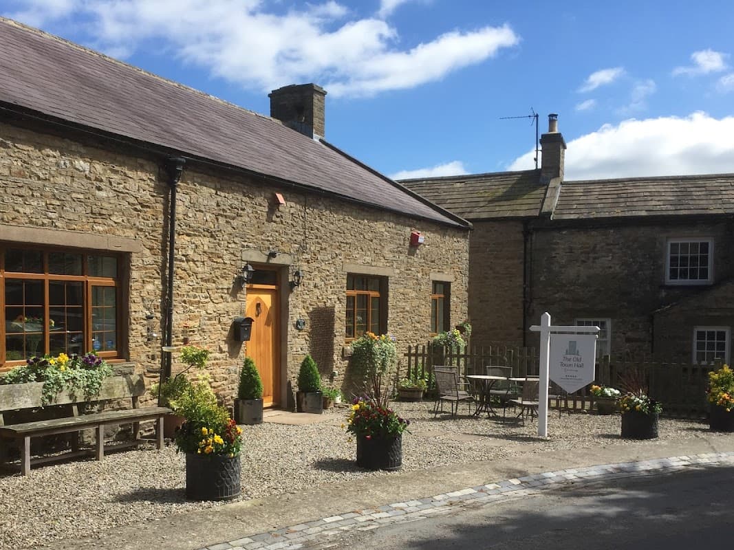 Charming stone building with flower pots, outdoor seating, and a welcoming sign in a picturesque Yorkshire village.