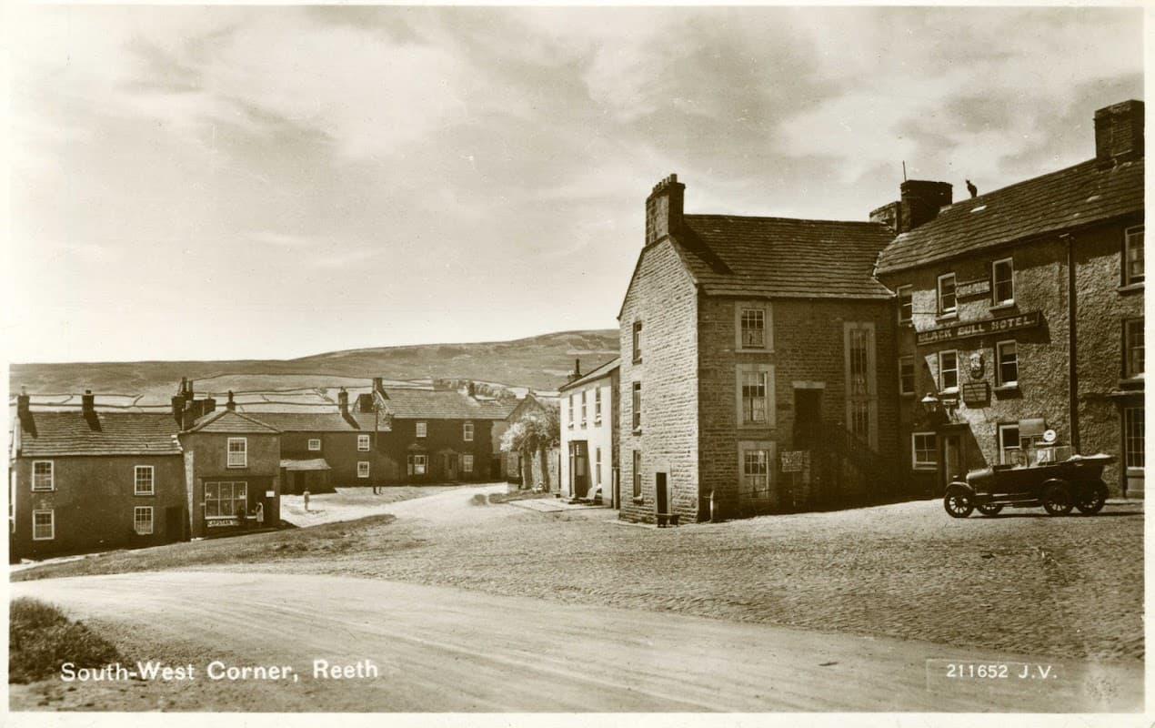 Historic street scene in Reeth, Yorkshire, featuring The Black Bull restaurant and surrounding stone buildings.