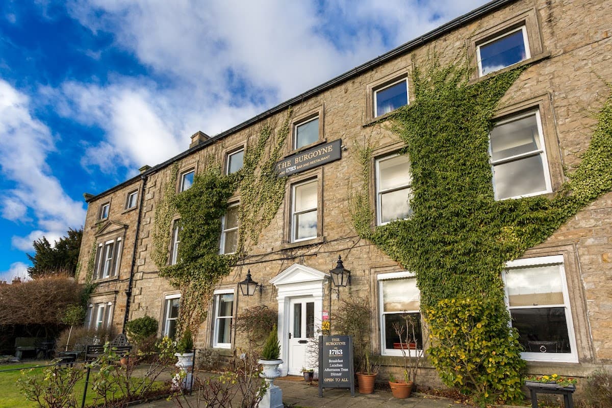 Historic stone building with ivy-covered walls, large windows, and a welcoming entrance in Reeth, Yorkshire.