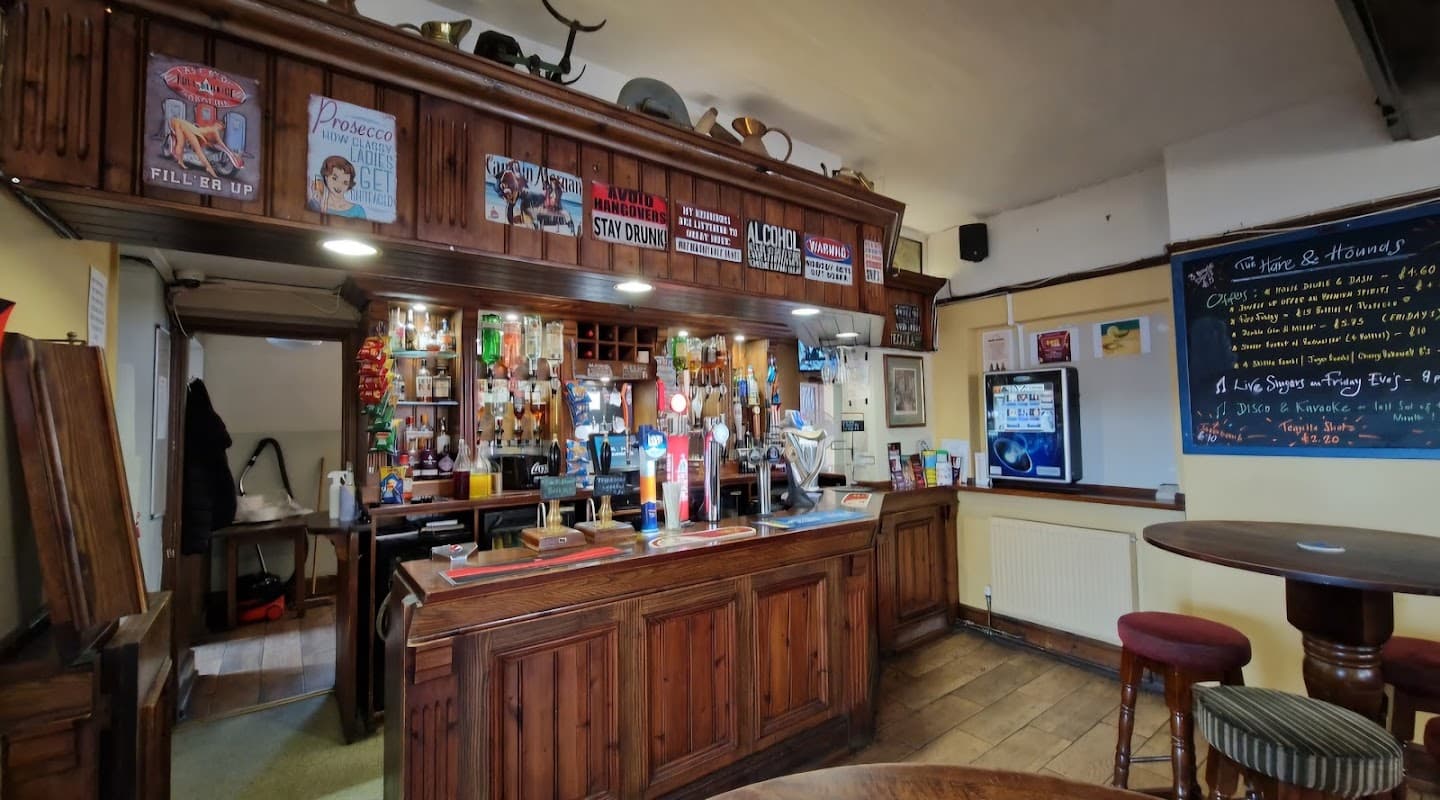 Rustic wooden bar with various drinks, vintage posters, and a chalkboard menu in a cozy restaurant setting.