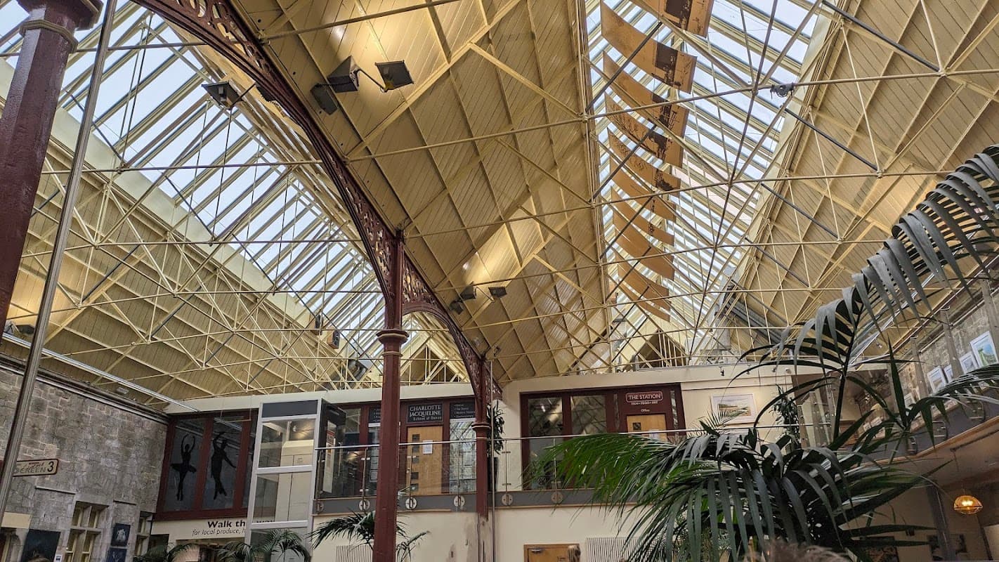 High ceiling with metal beams, large windows, and indoor plants in a spacious recreational area.