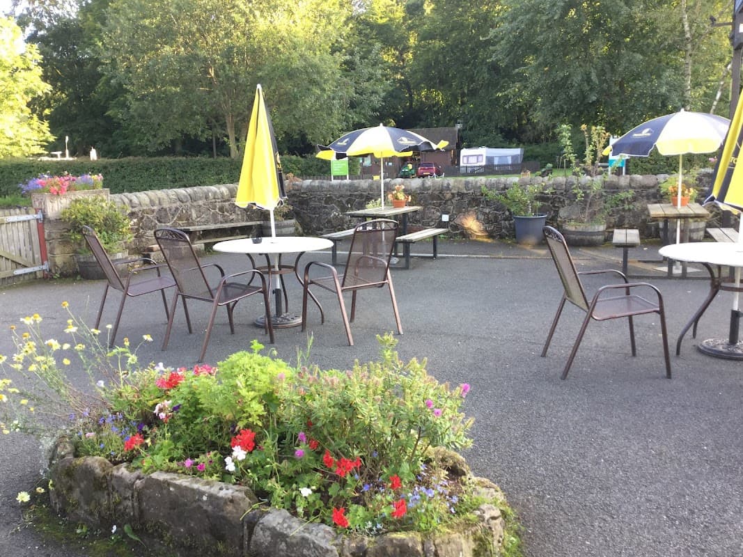 Outdoor seating area with tables and chairs, surrounded by vibrant flowers and umbrellas at The Coach House Inn.