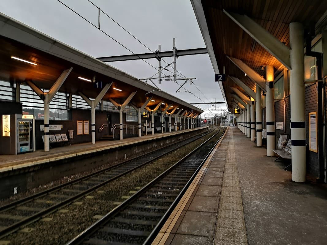 Platform view at Rotherham Central station, featuring overhead lines, waiting areas, and illuminated signage.