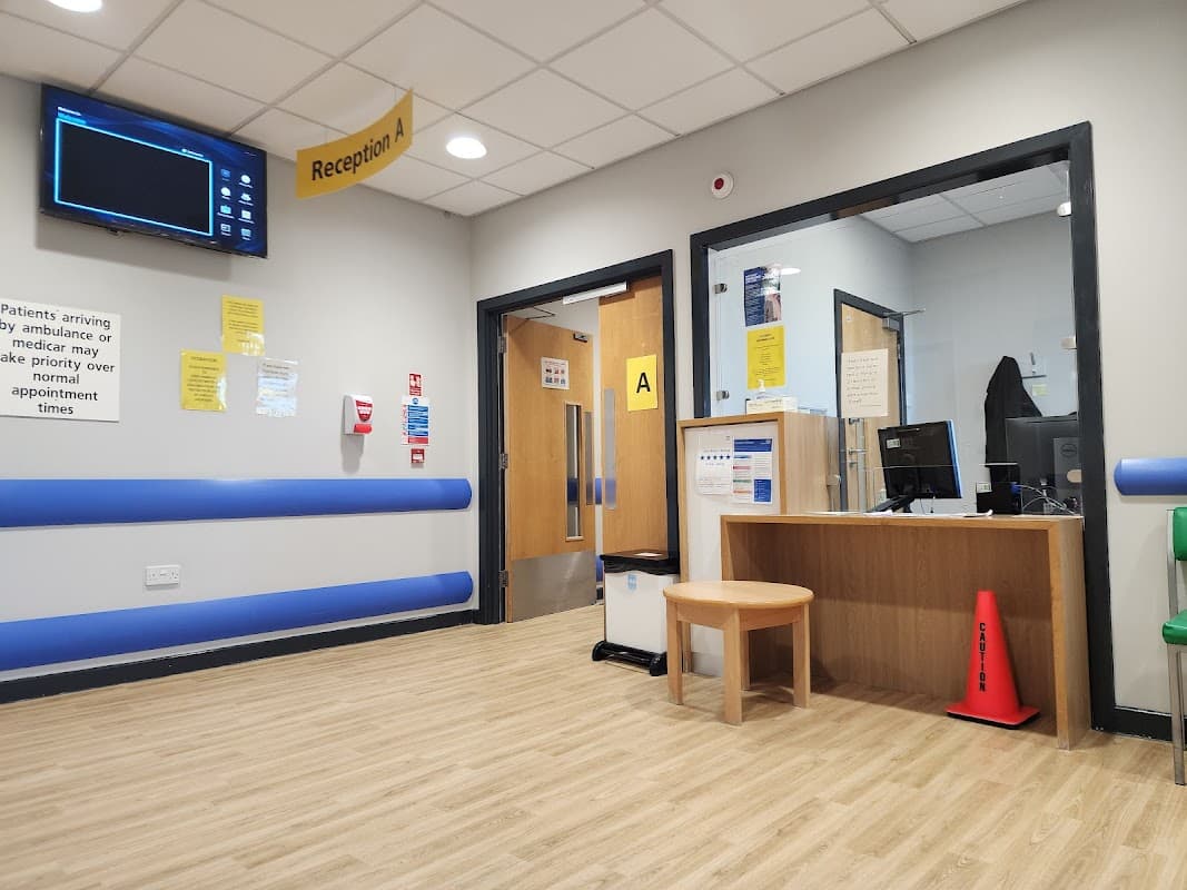 Reception area of Rotherham Community Health Centre with wooden desk, seating, and informational signage.