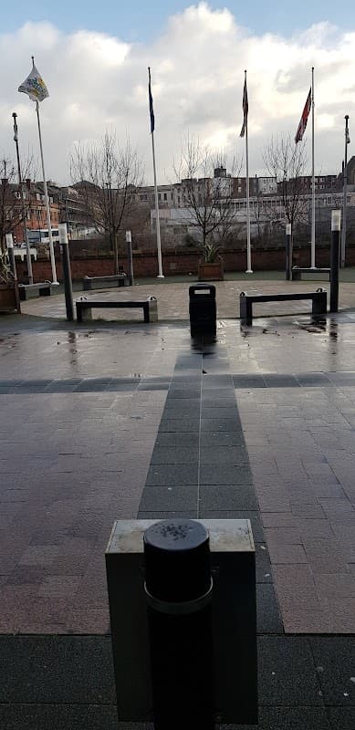 Pay & Display parking area with flags, trees, and a cloudy sky in Rotherham, Yorkshire.