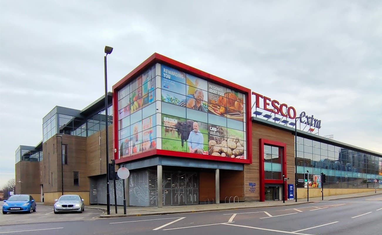 Large Tesco Extra store with modern architecture, featuring colorful advertisements and a parking area in Rotherham.