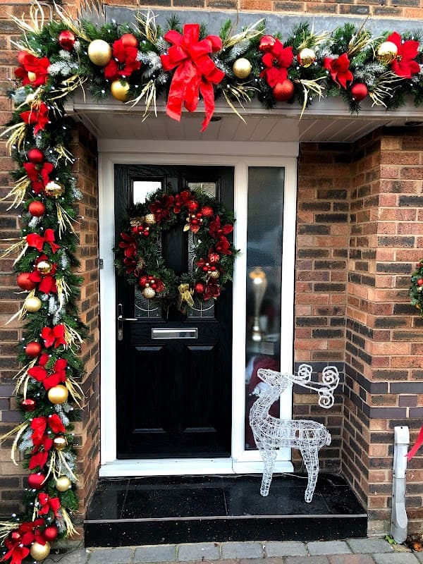 Festive entrance with a decorated door, wreath, garland, red bows, and a glowing reindeer figure.