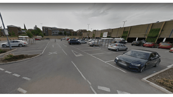 Pay & Display parking area in Rotherham, featuring empty spaces and parked cars under a cloudy sky.
