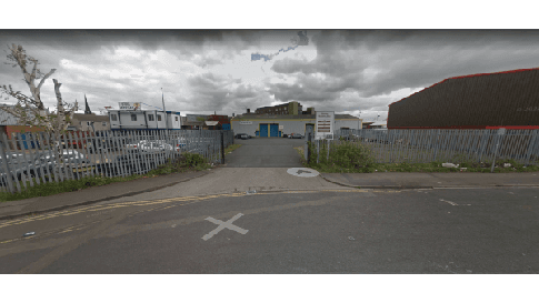 Pay & Display parking area entrance in Rotherham, surrounded by a metal fence and industrial buildings under cloudy skies.
