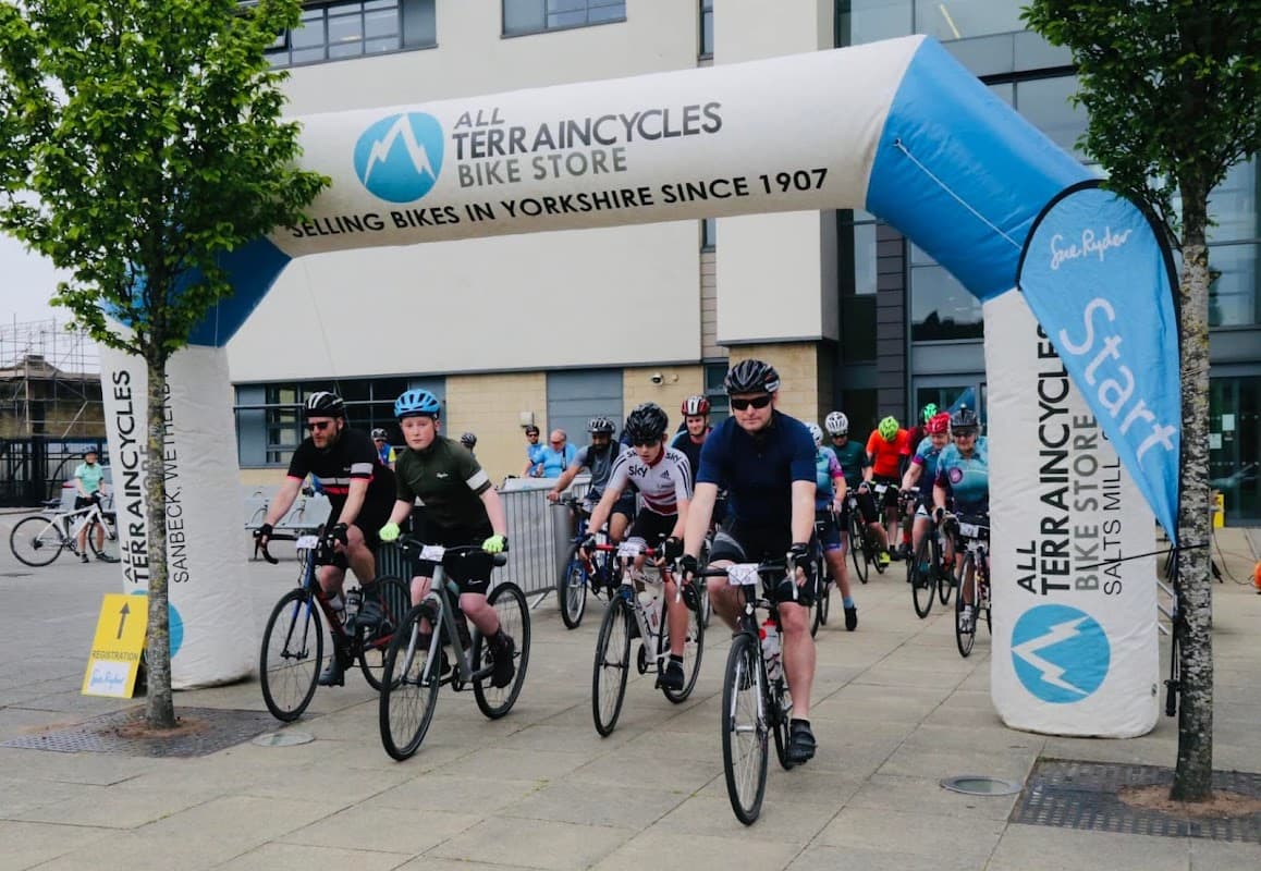 Cyclists begin a ride under a large inflatable arch with "All Terrain Cycles" in Saltaire, Yorkshire.
